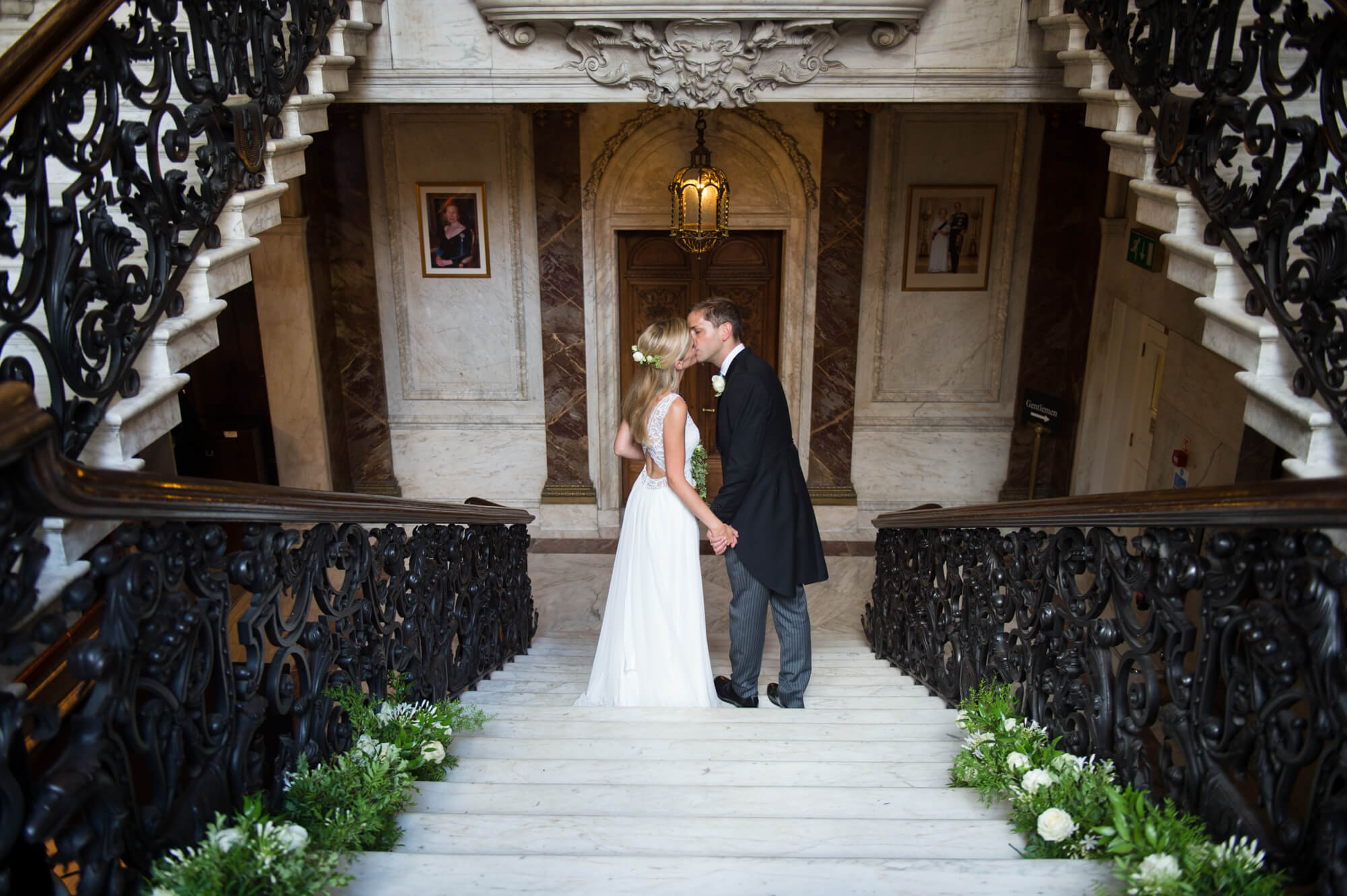The bride and groom kissing on the staircase at Dartmouth  house in Mayfair, London